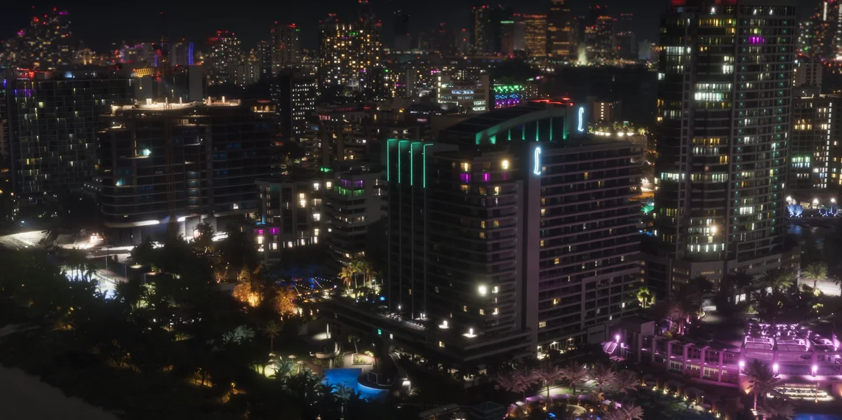Panorámica nocturna de Vice City con rascacielos iluminados, neones y reflejos sobre el agua
